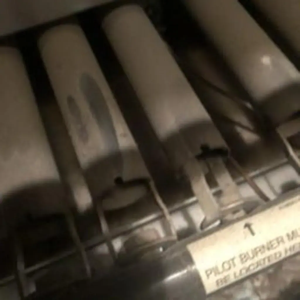 Gas furnace in-shot burners and pilot burner label during a heating repair in White Plains, NY